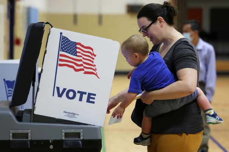 Photo for story: A voter casts her ballot with her child in in Virginia, one of two states holding gubernatorial elections in 2025