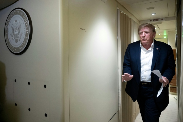Photo for story: US President Donald Trump speaks to the press aboard Air Force One